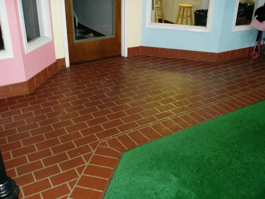 A room with a brick floor and a green rug