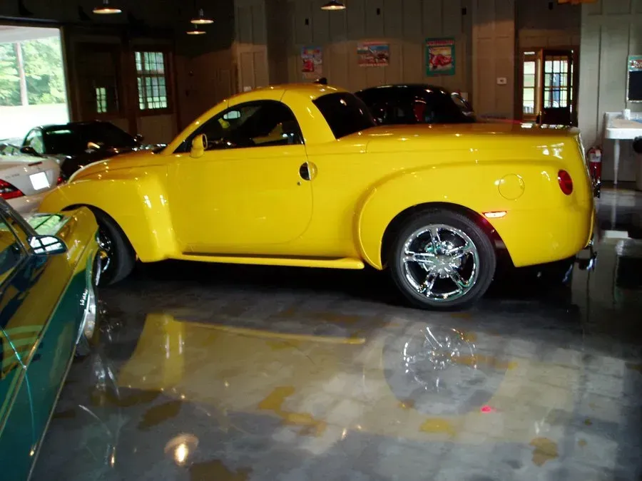 A yellow truck is parked in a garage with other cars