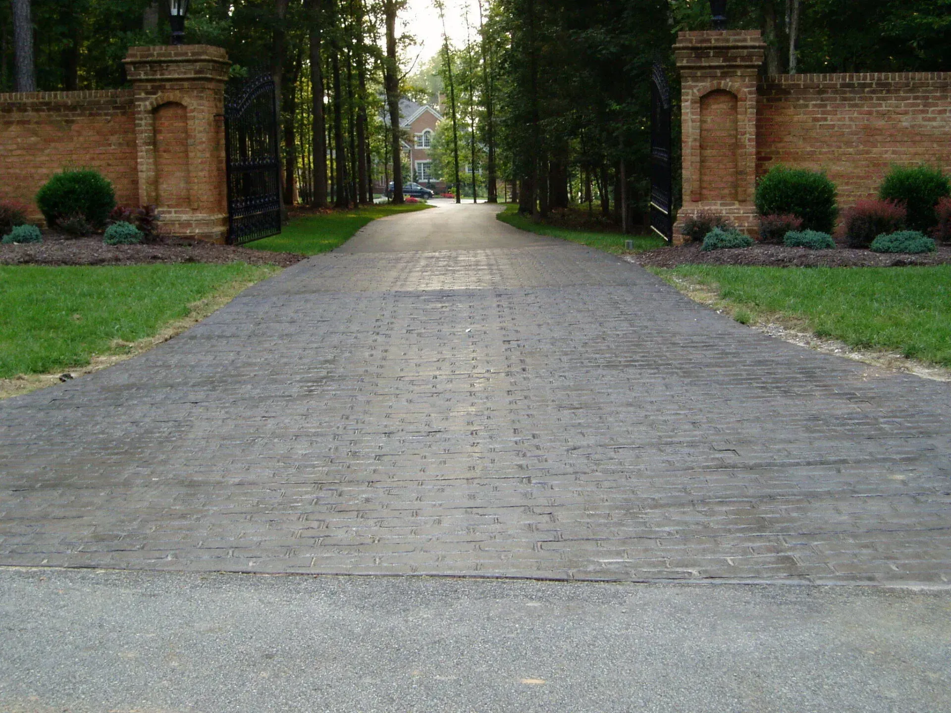 A brick driveway leading to a brick gate