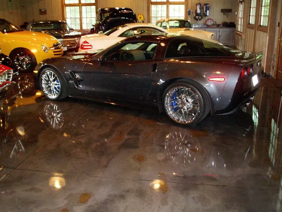 A gray sports car is parked in a garage with other cars