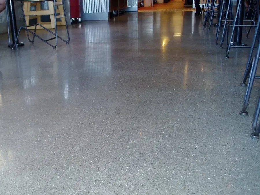 A shiny concrete floor in a room with tables and chairs