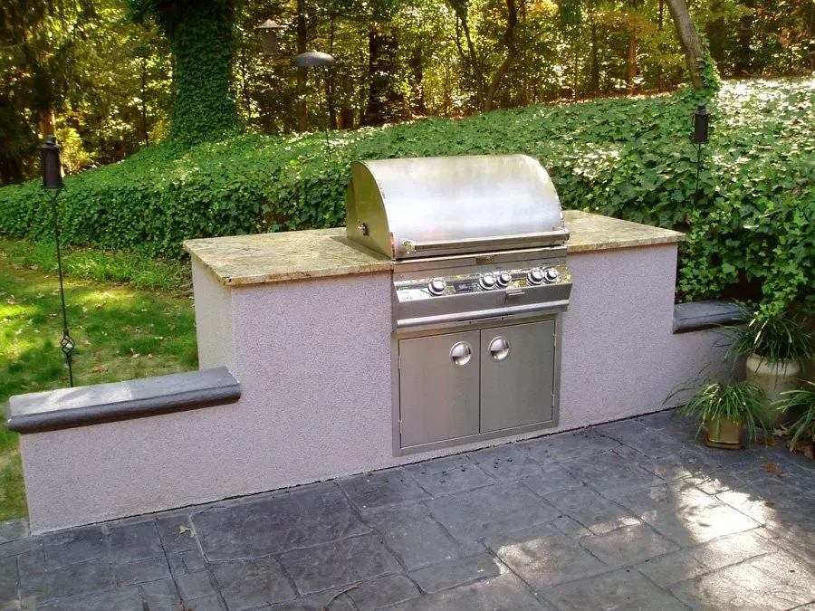 A stainless steel grill is sitting on top of a stone counter.