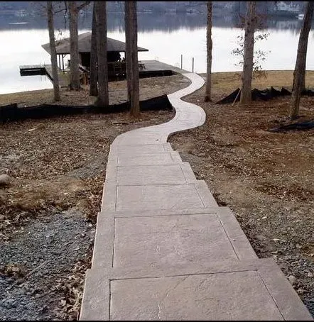 A concrete walkway leads to a dock on a lake