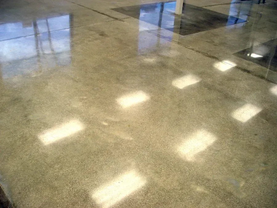 A close up of a shiny concrete floor with lights reflecting off of it.