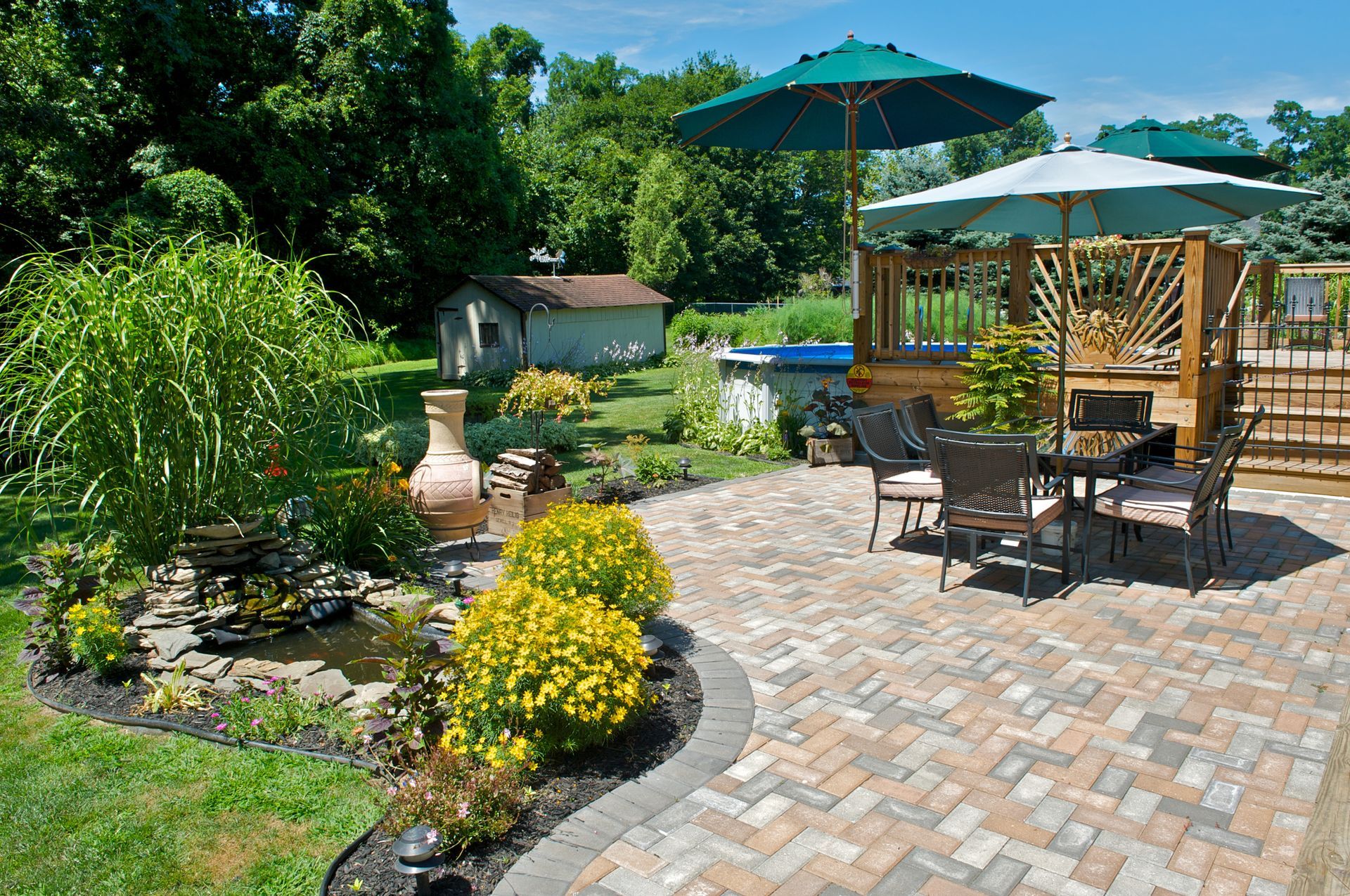 A decorative concrete patio featuring a table, chairs, and a large umbrella for shade.