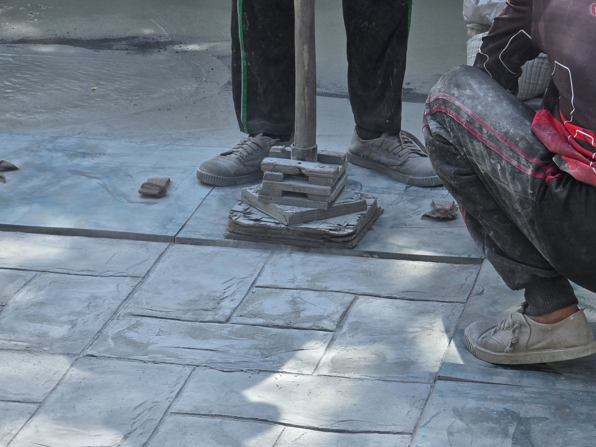 A man hammers a concrete floor, showcasing the process of creating commercial stamped concrete.