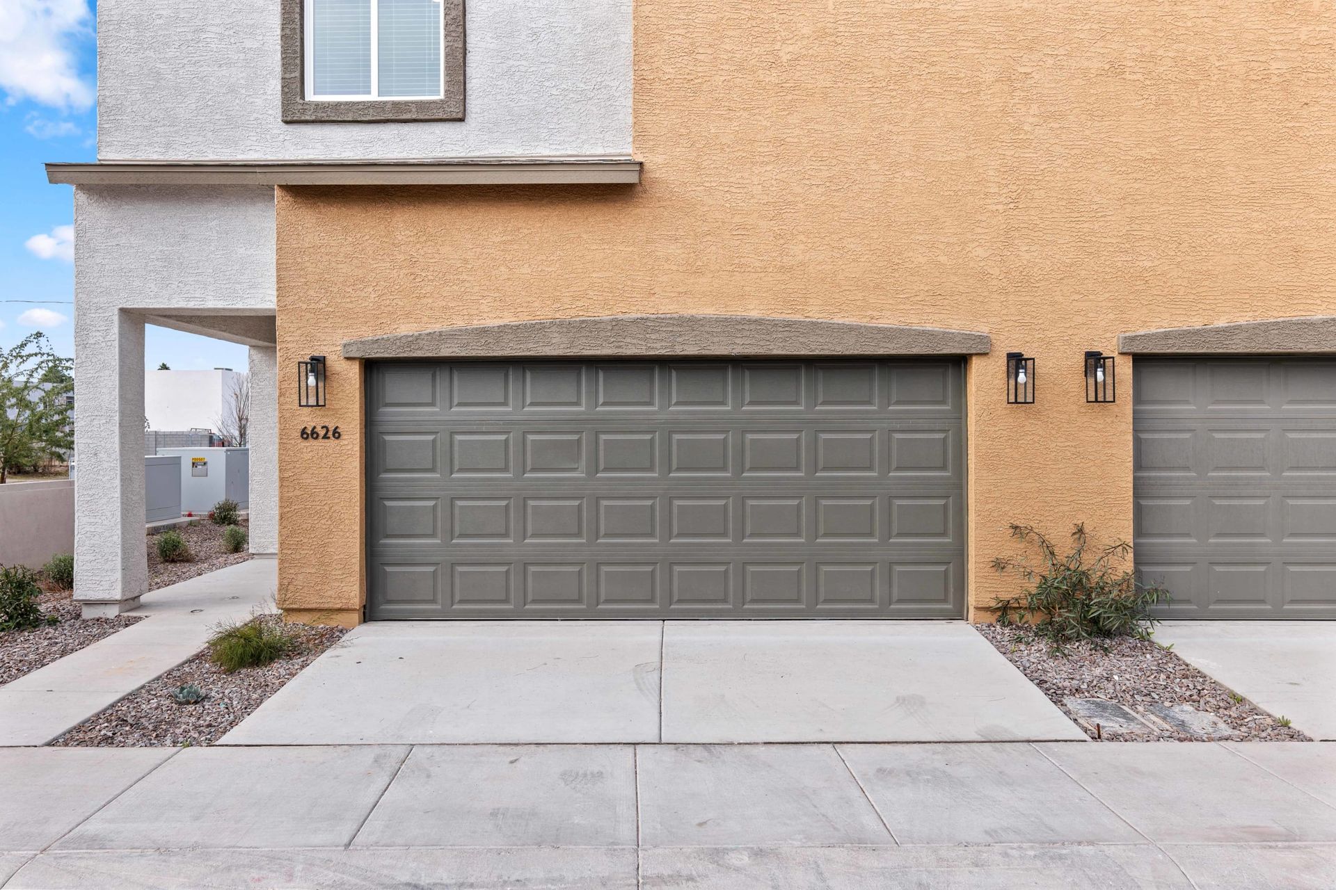 Suburban house exterior with tan stucco and a gray two-car garage door