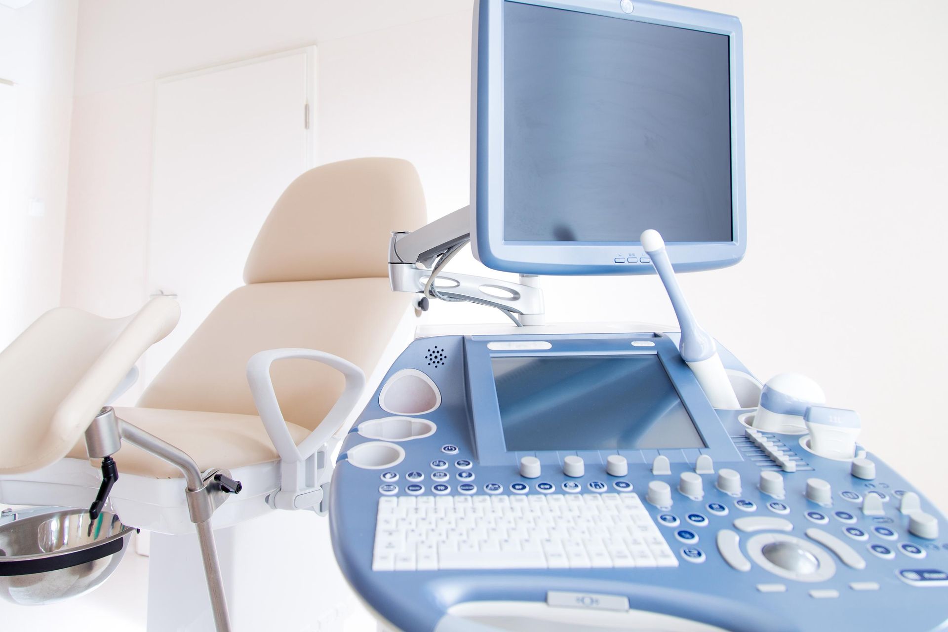 Ultrasound machine next to an examination chair in a medical office.