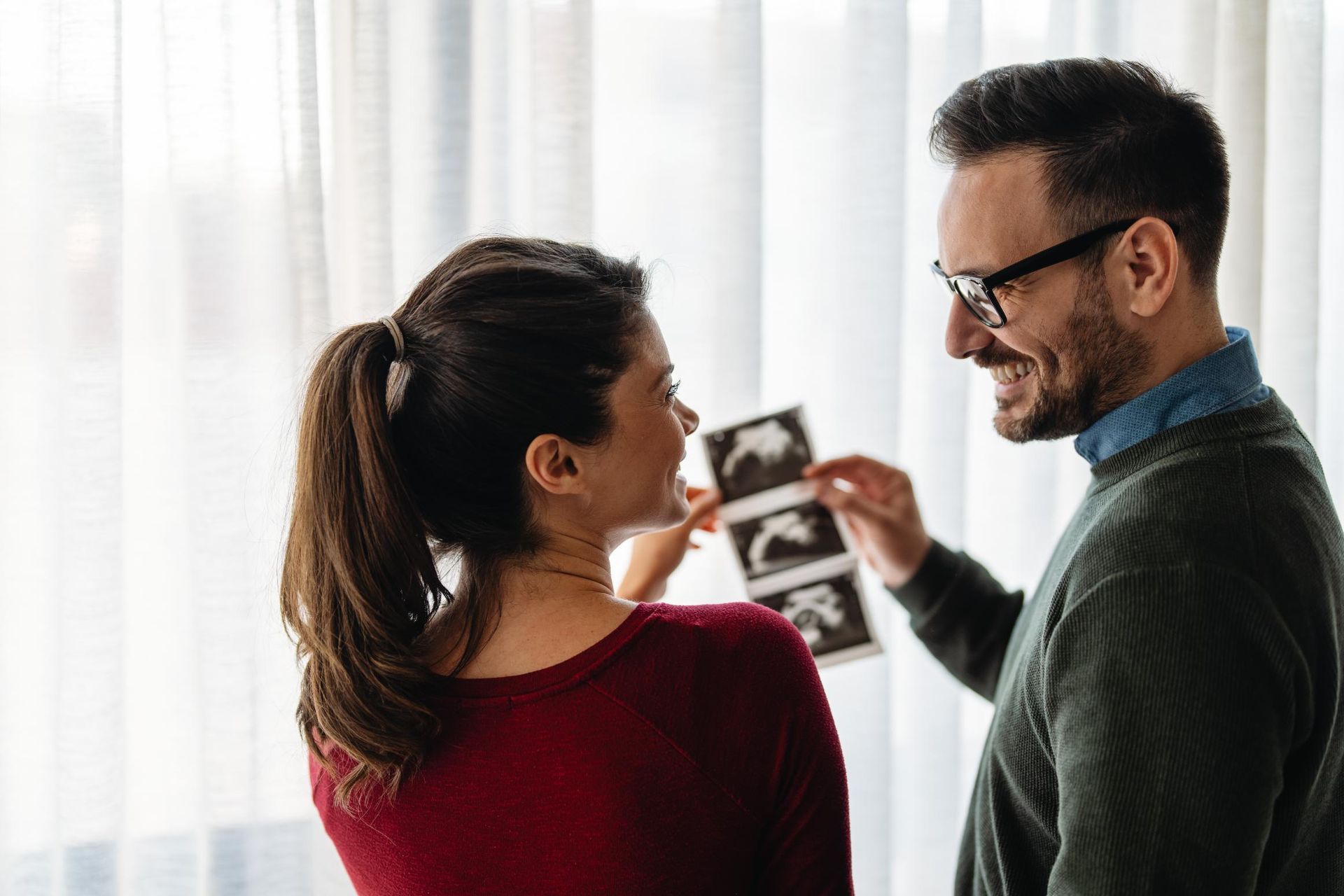 Couple looking at ultrasound images, man smiling.
