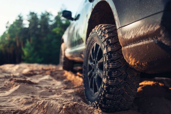 Close-up of a muddy off-road tire on a vehicle driving through a dirt trail