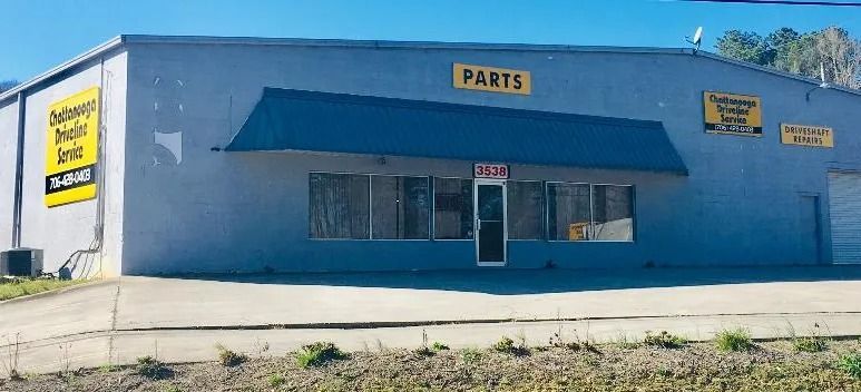 Blue auto parts store with a dark awning and front windows under a clear sky
