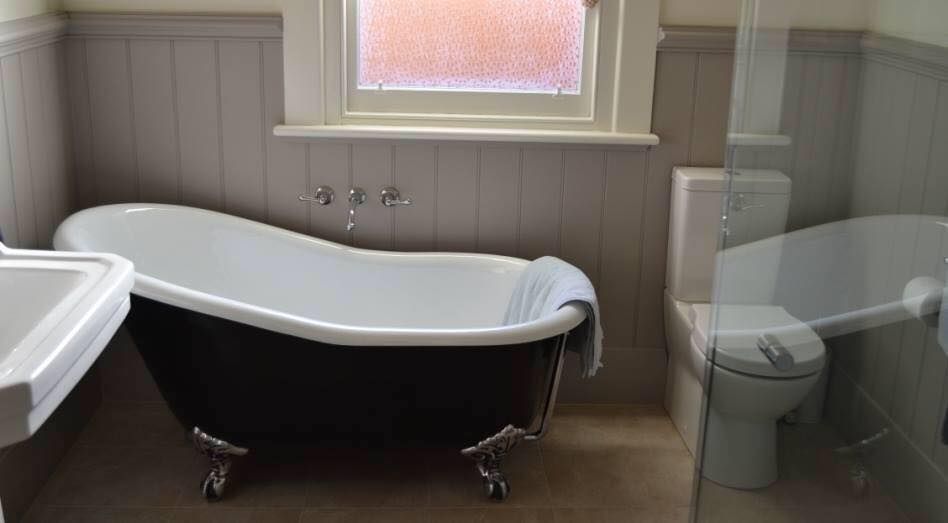 A bathroom with a bathtub , sink , toilet and window.