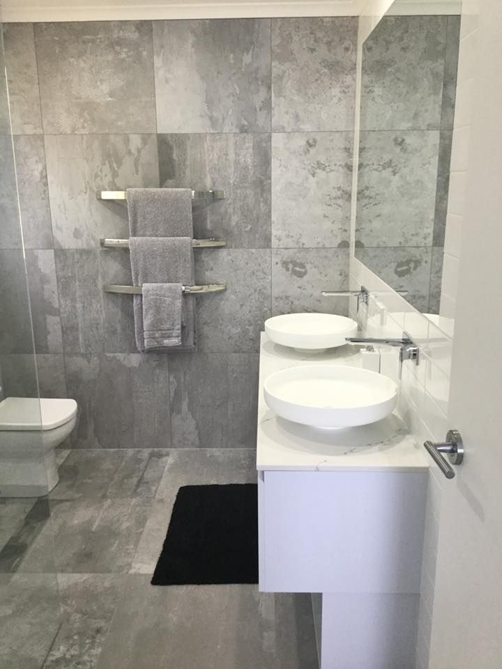 A bathroom with two sinks , a toilet and a mirror.