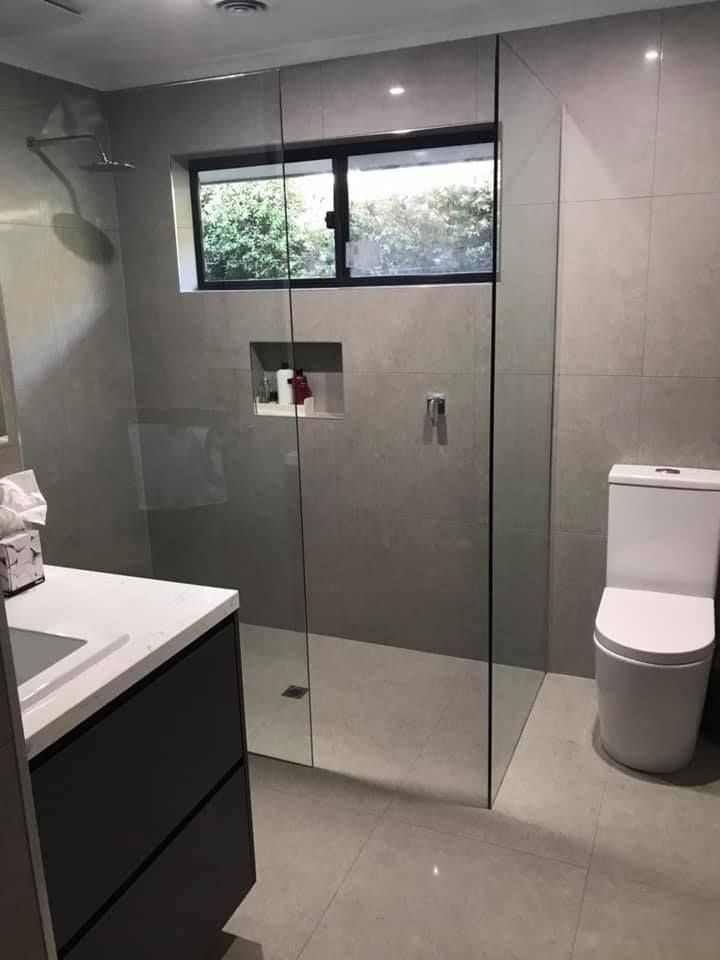 A bathroom with a toilet , sink and walk in shower.