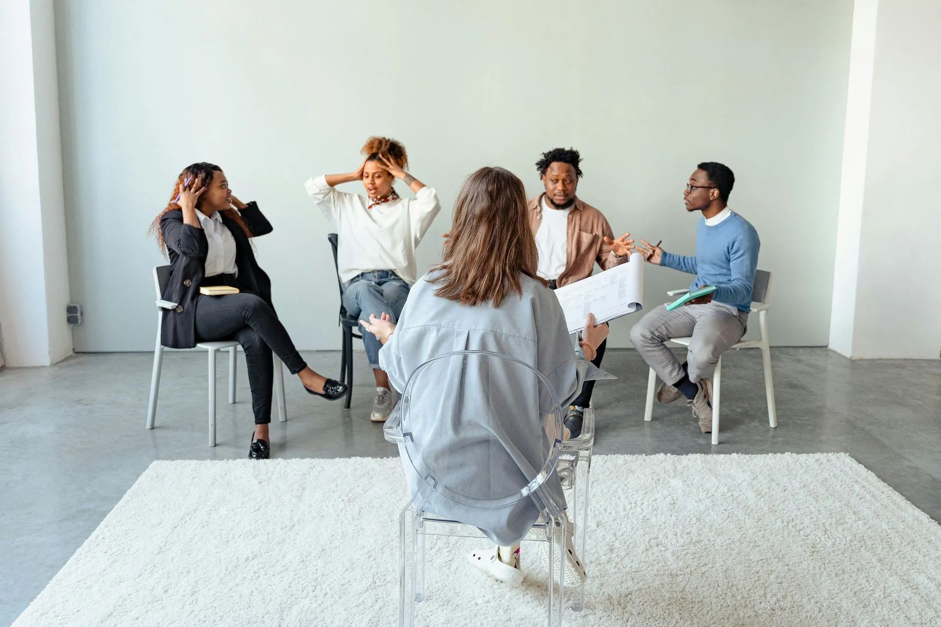 Five people seated in a bright room, talking in a small group discussion area