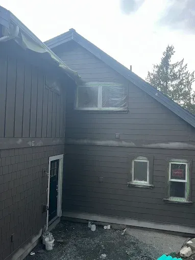Brown house exterior with windows covered, under construction.