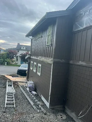 Exterior of a brown house under construction with ladders and building materials visible.