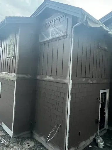 Brown building exterior being painted with white trim.