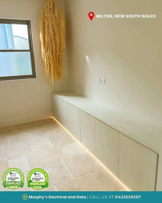 Interior room in Milton, NSW with built-in cabinet, window, decorative hanging art, and electrical outlets.