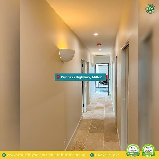 Narrow hallway with light beige walls, sconce, stone floor, doors. Princess Highway, Milton.