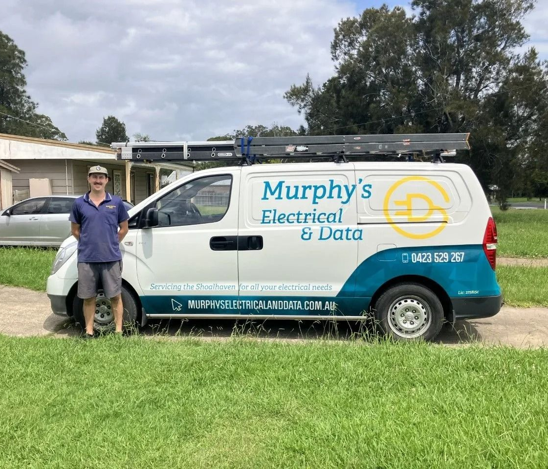 Man stands next to a white service van with turquoise detailing, branded 