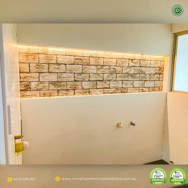 Bathroom with brick-style accent wall, white tile, and warm lighting.