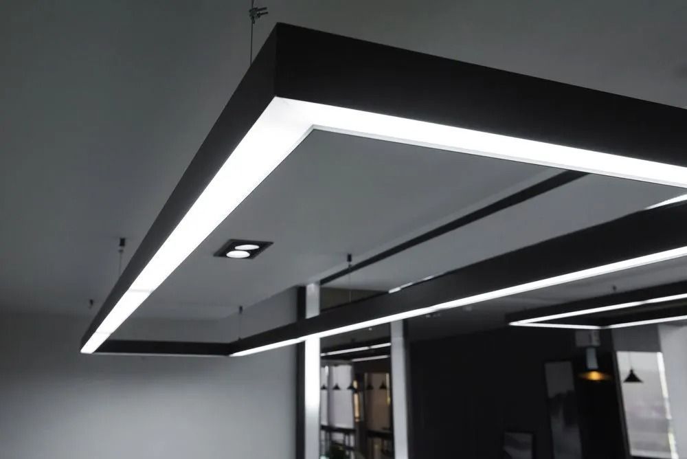 Rectangular black and white overhead LED lights, recessed in the ceiling of a modern space.
