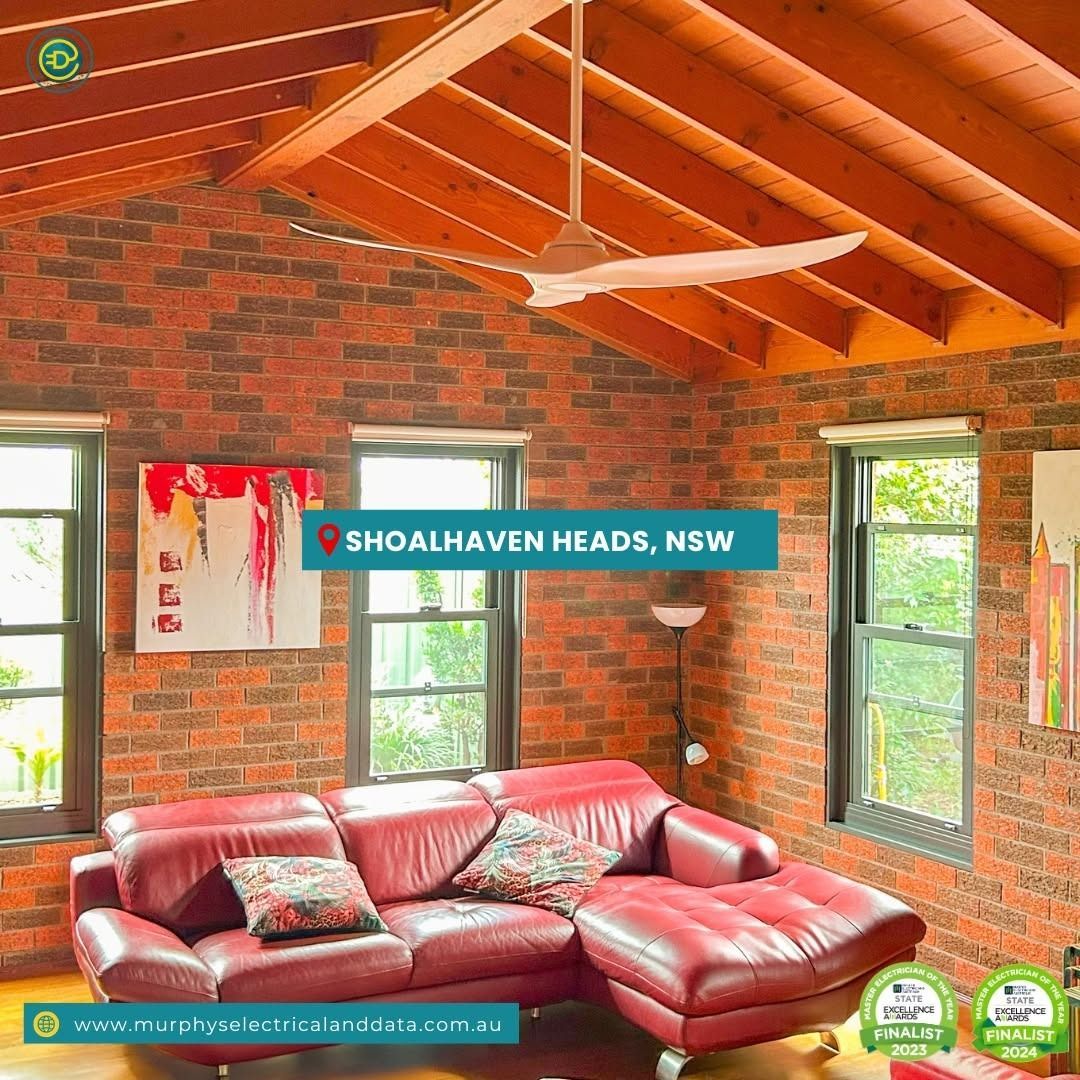 Red brick living room with leather couch, windows, and ceiling fan in Shoalhaven Heads, NSW.