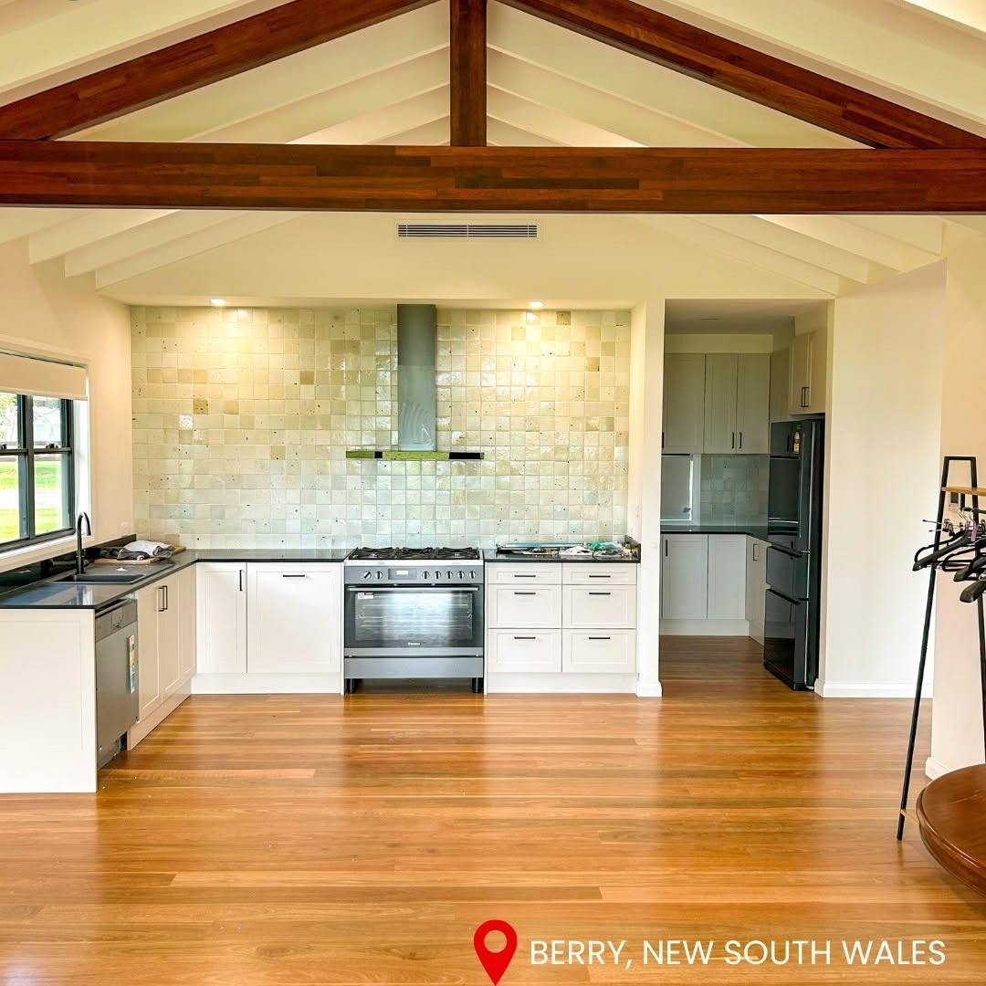 Spacious kitchen with wooden floors and beams. White cabinets, stainless steel appliances. Berry, NSW.