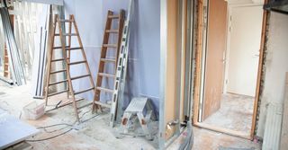 A room under construction with a ladder and a stool.