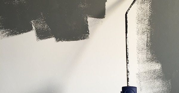 A person is painting a wall with a paint roller.