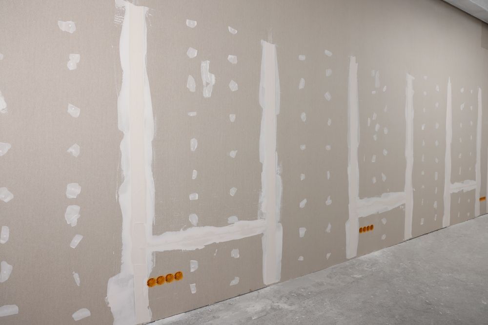 A room with a row of drywall walls and electrical outlets.