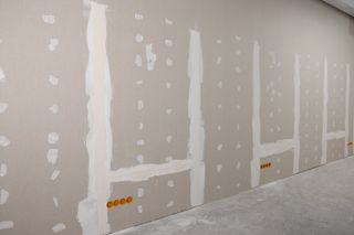 A room with a row of drywall walls and electrical outlets.