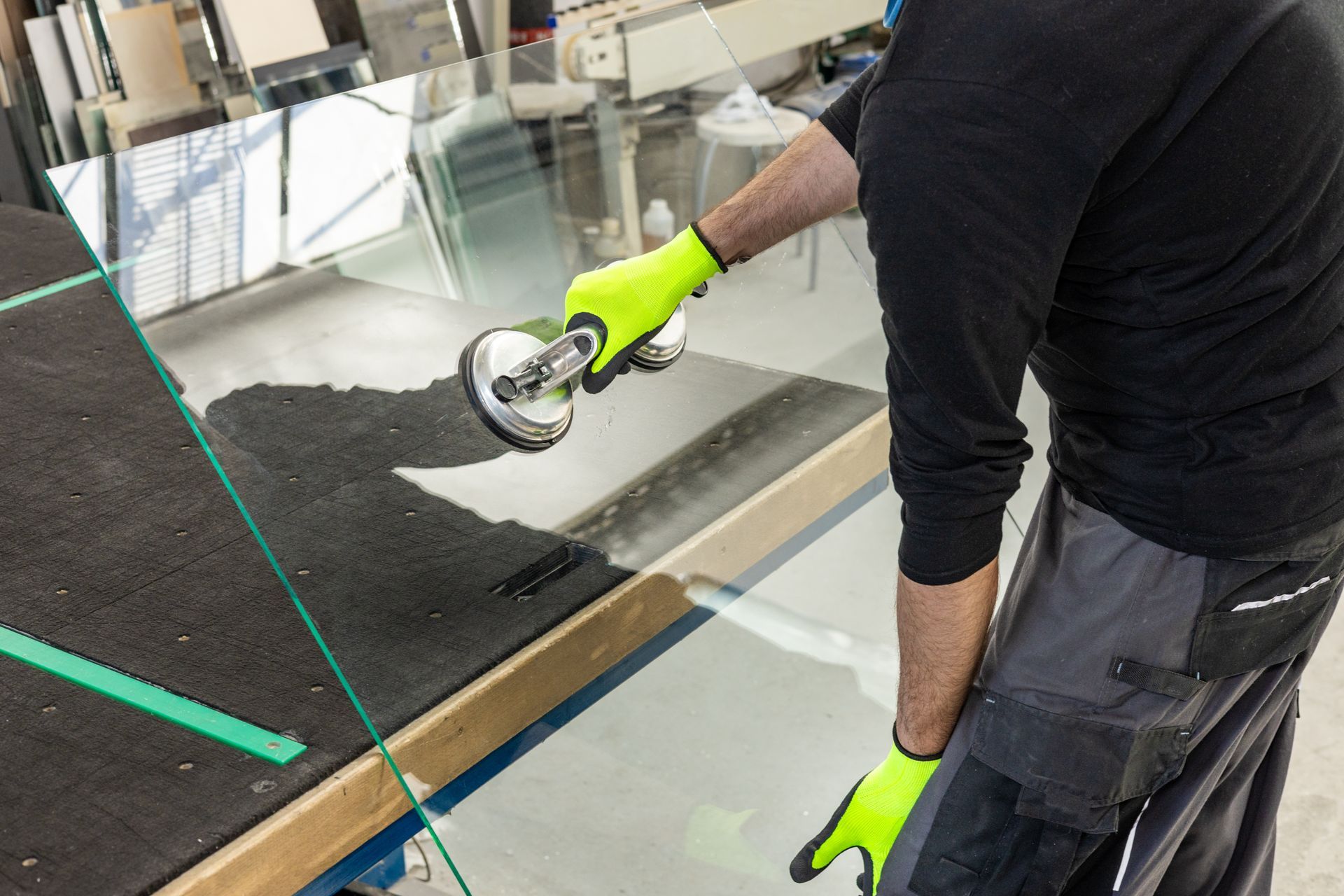 A glazier lifts the glass in a factory using a special glass suction cup.