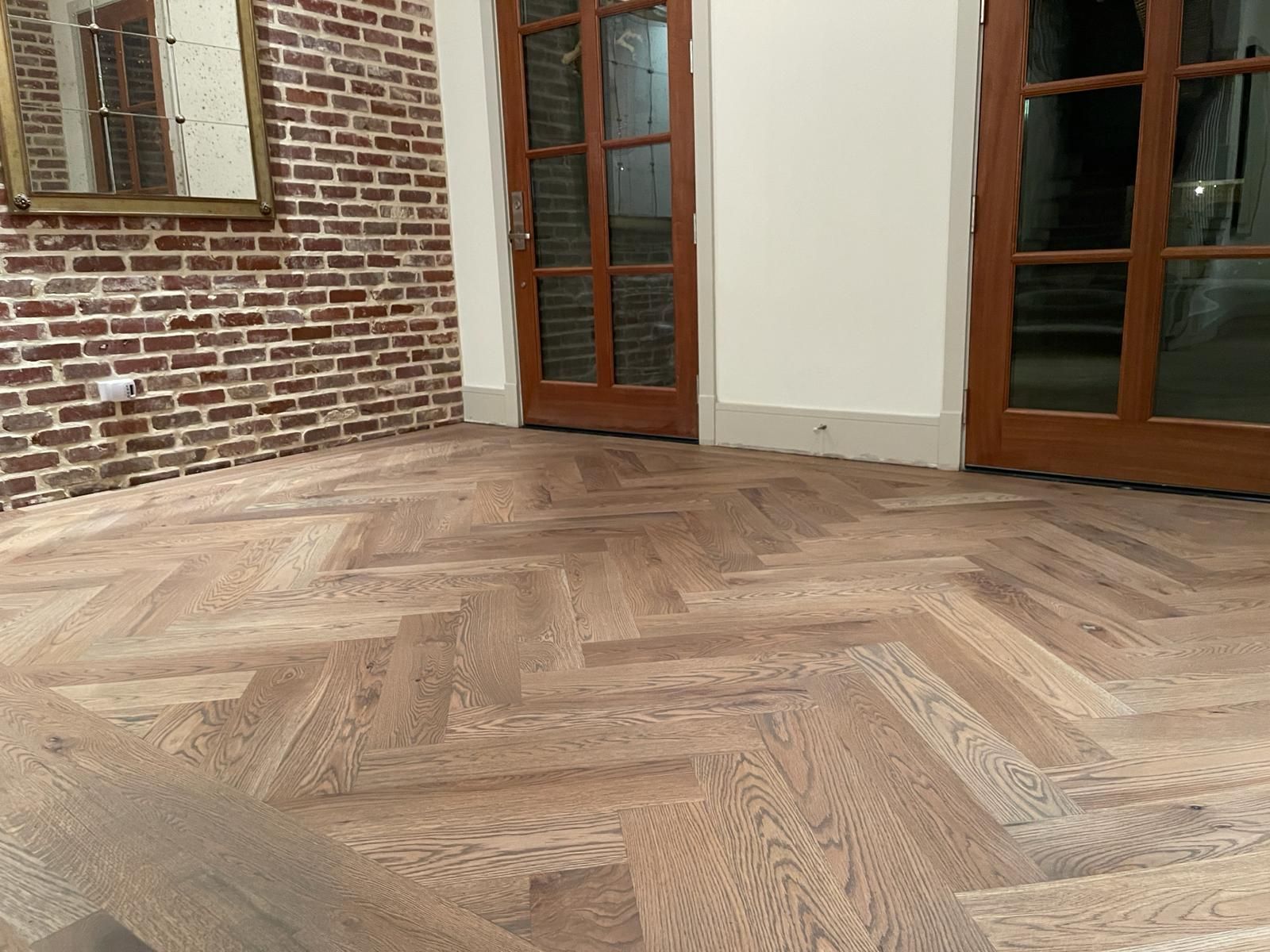 A room with a wooden floor and a brick wall.