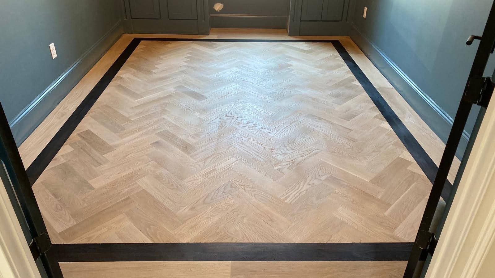 A wooden floor with a herringbone pattern and a black border