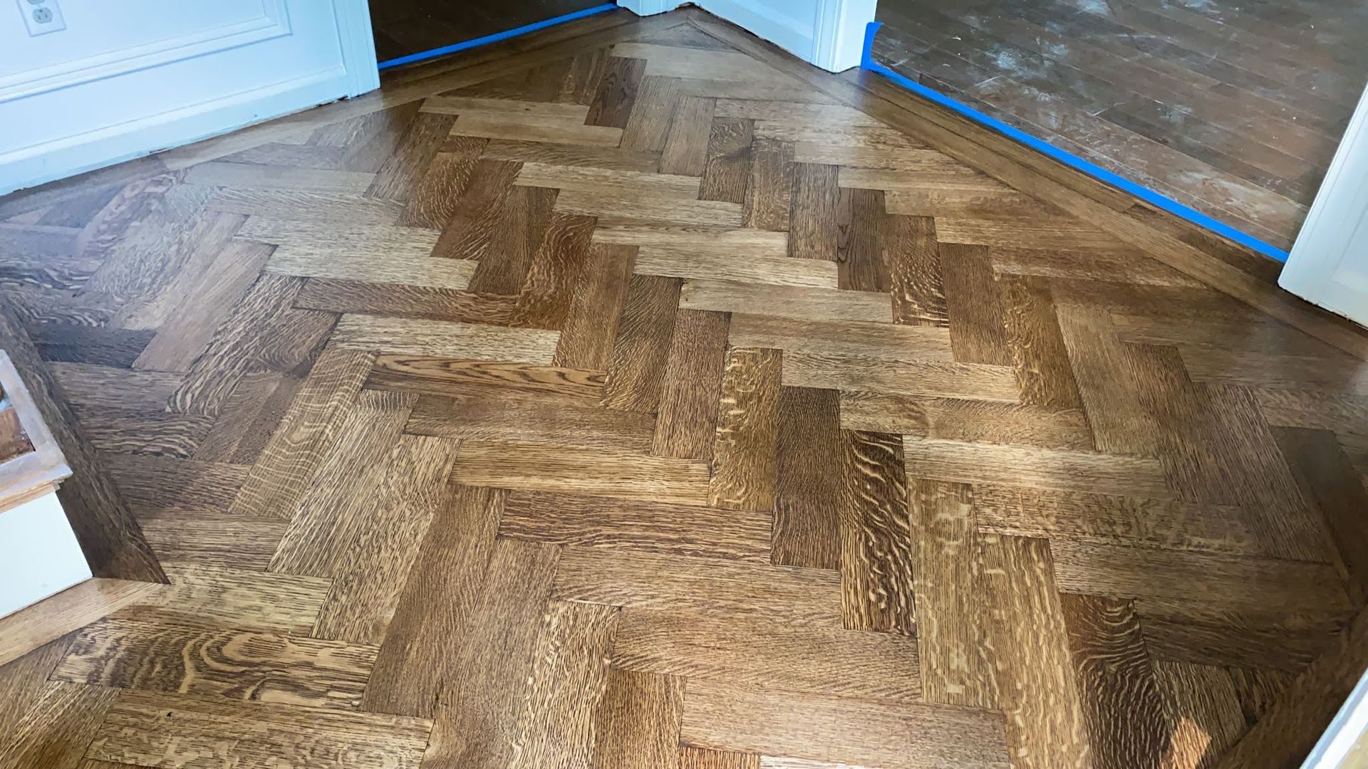 A close up of a wooden floor with a herringbone pattern.