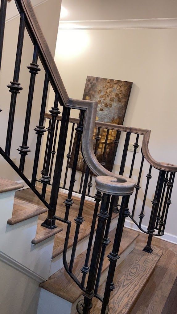 A staircase with a wrought iron railing and a painting on the wall.