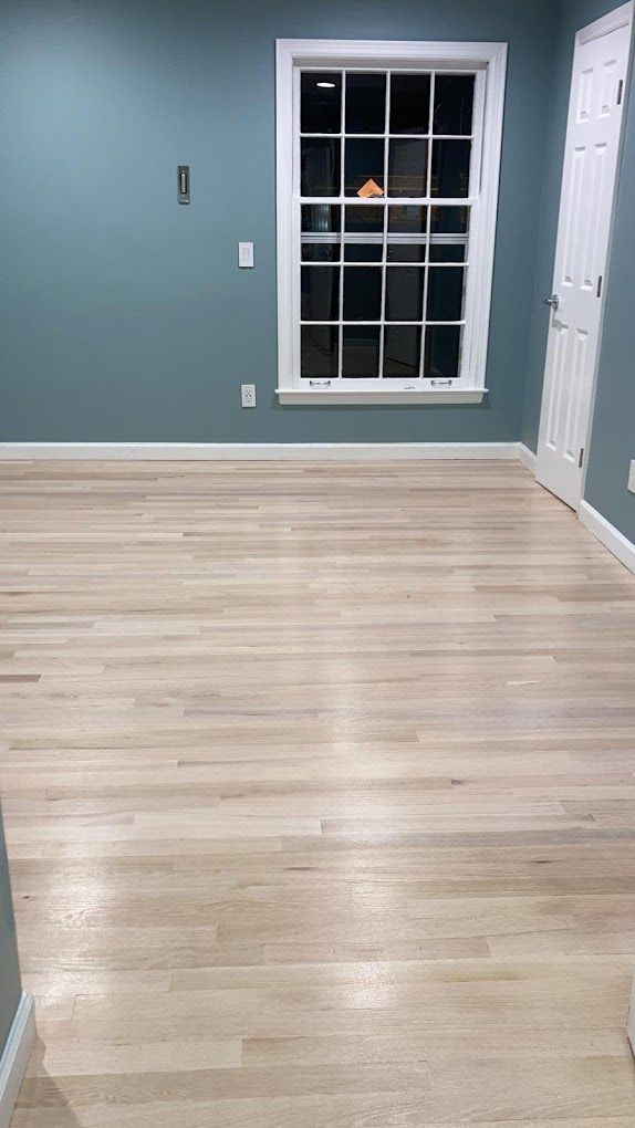 An empty room with hardwood floors and a window.