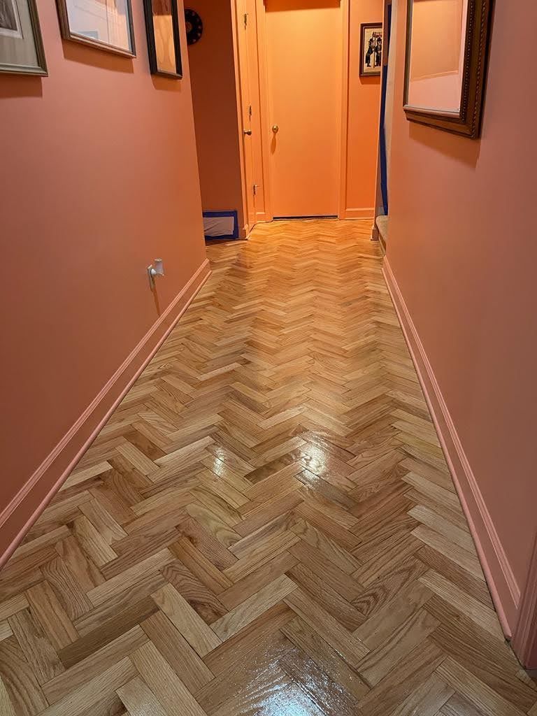 A hallway with a wooden floor and pink walls.