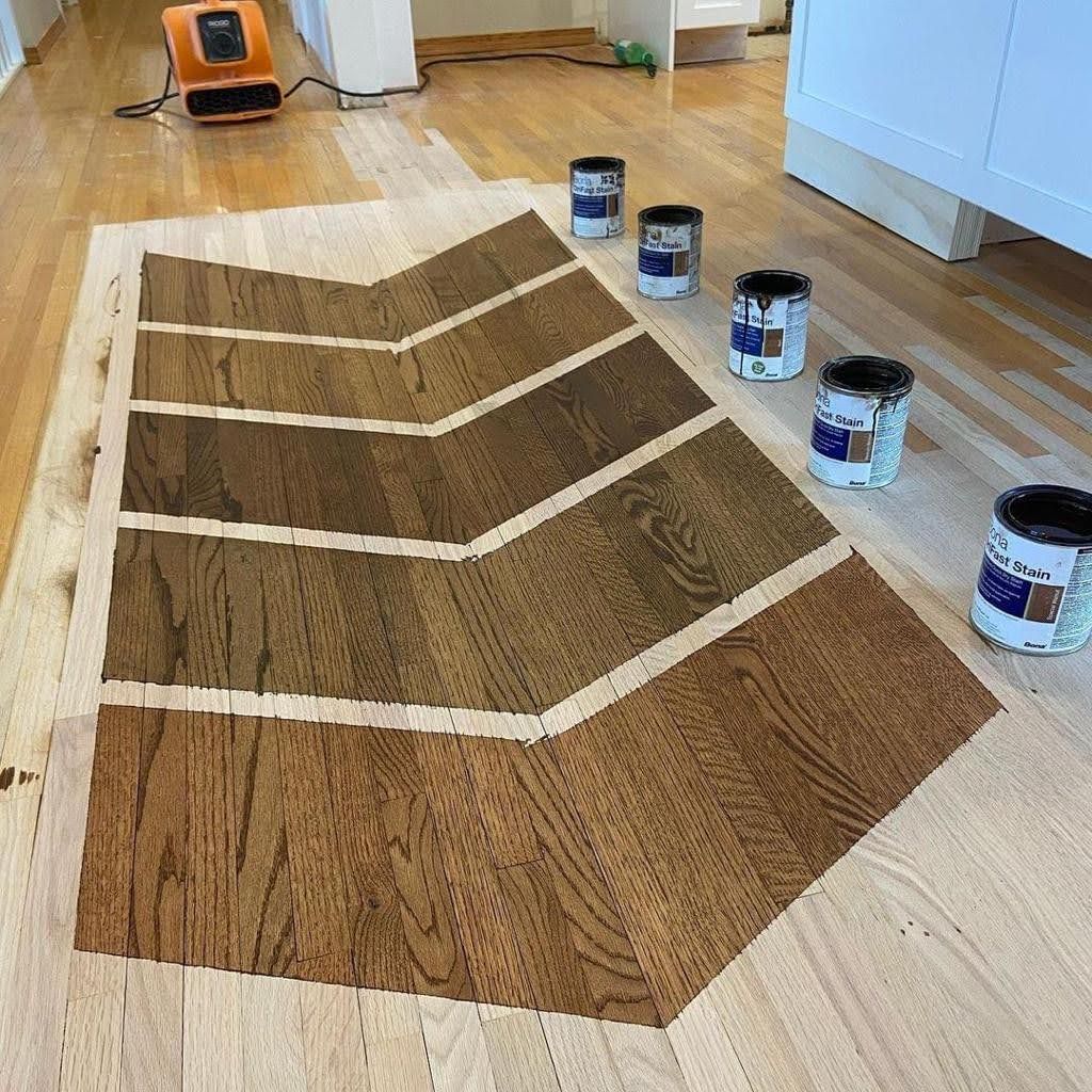 A wooden floor with a chevron pattern and cans of paint on it.