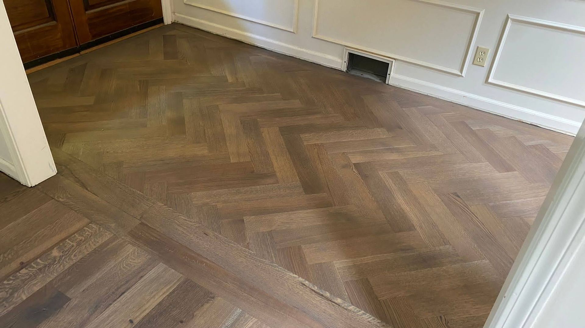 A wooden floor with a herringbone pattern in a room.