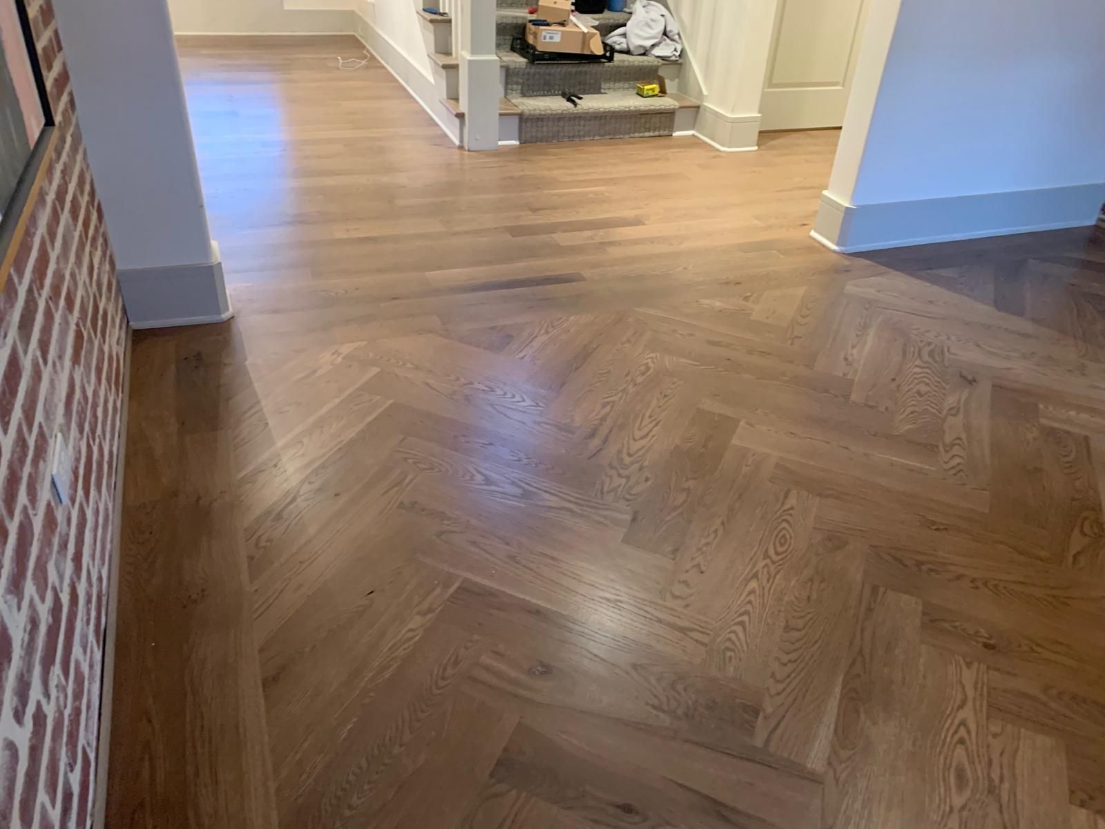 A wooden floor with a herringbone pattern in a hallway.