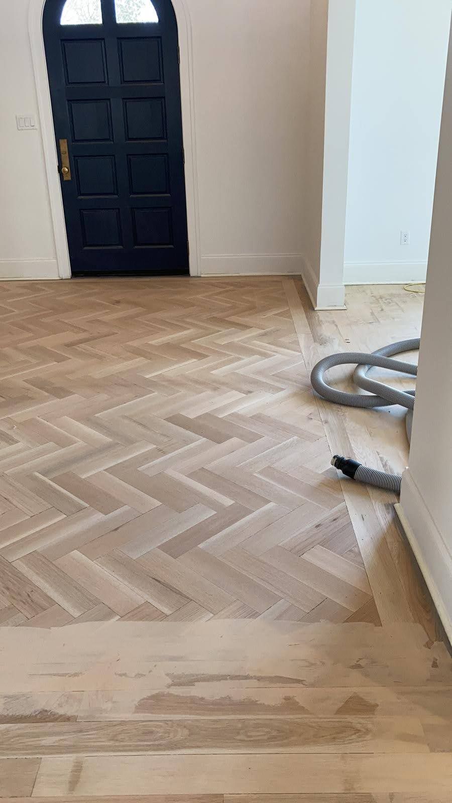 A wooden floor with a herringbone pattern in a room with a door.