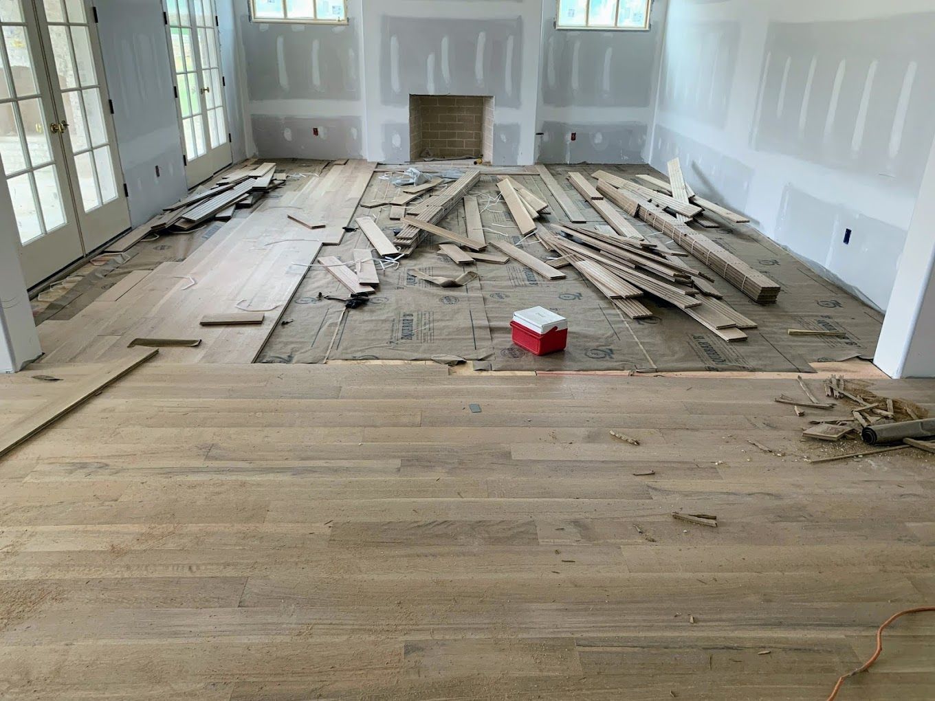 A living room with wooden floors and a fireplace under construction.