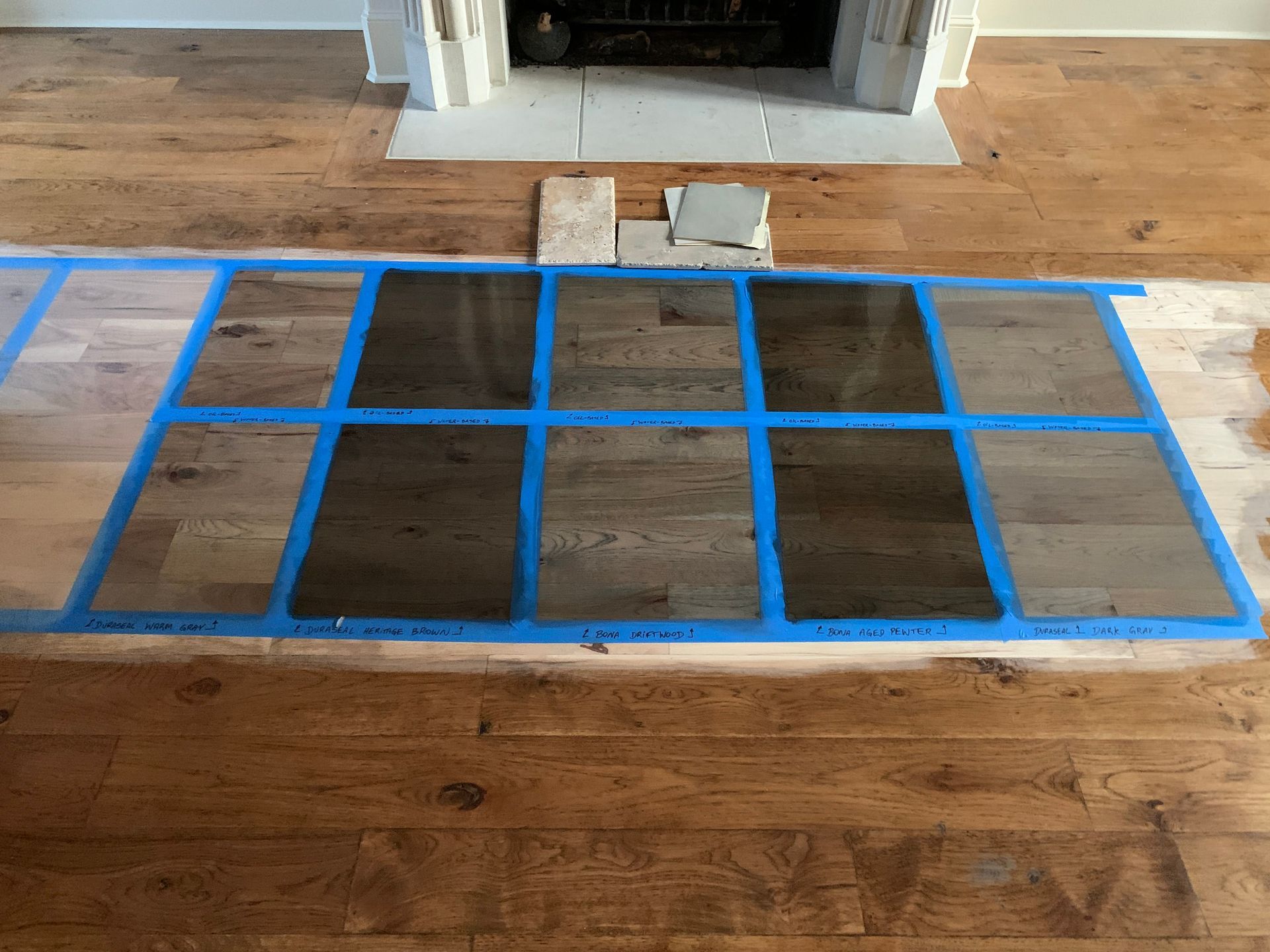 A wooden floor with a fireplace in the background and blue tape on it.