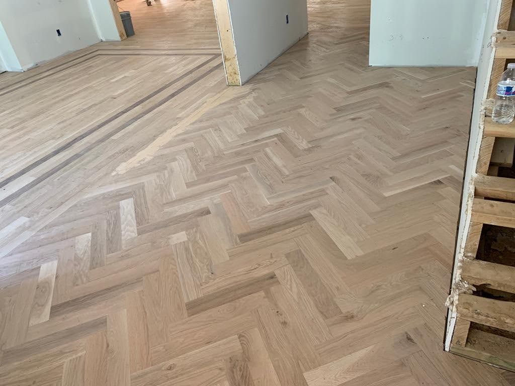 A wooden floor with a herringbone pattern in a room.