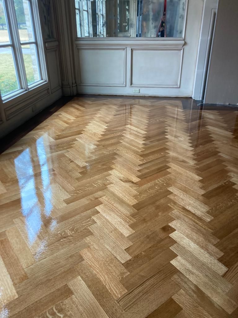 A room with a herringbone wooden floor and a window.