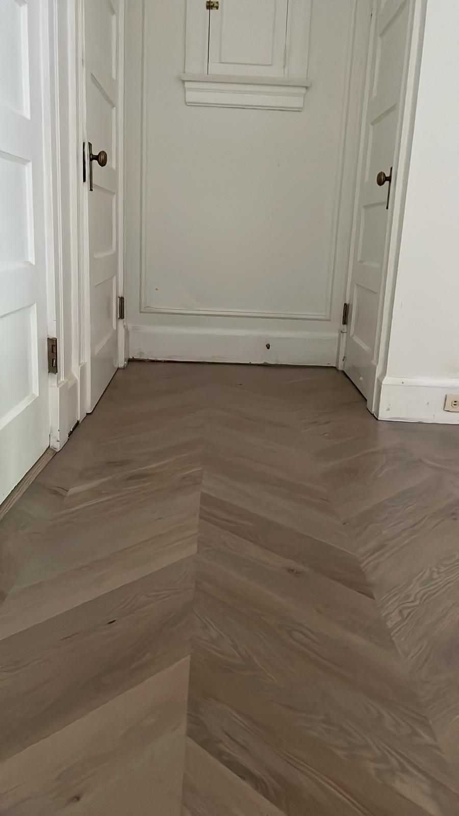 A hallway with a wooden floor and white doors.