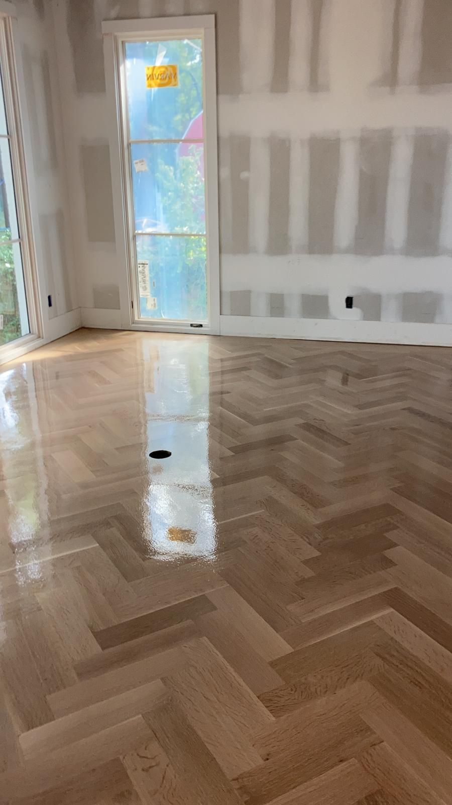 A room with a herringbone wood floor and a window.